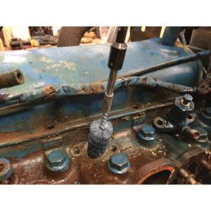 a person is cleaning a rusty engine with a brush